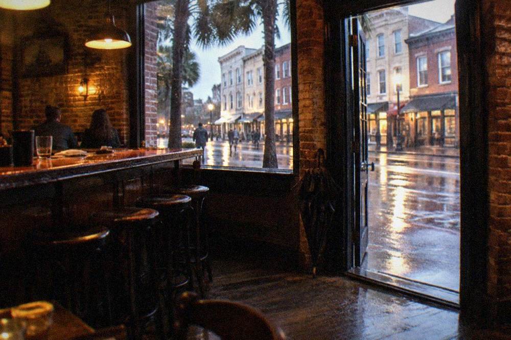 Warm-lit bar interior with brick walls, high stools and a chalkboard drinks menu