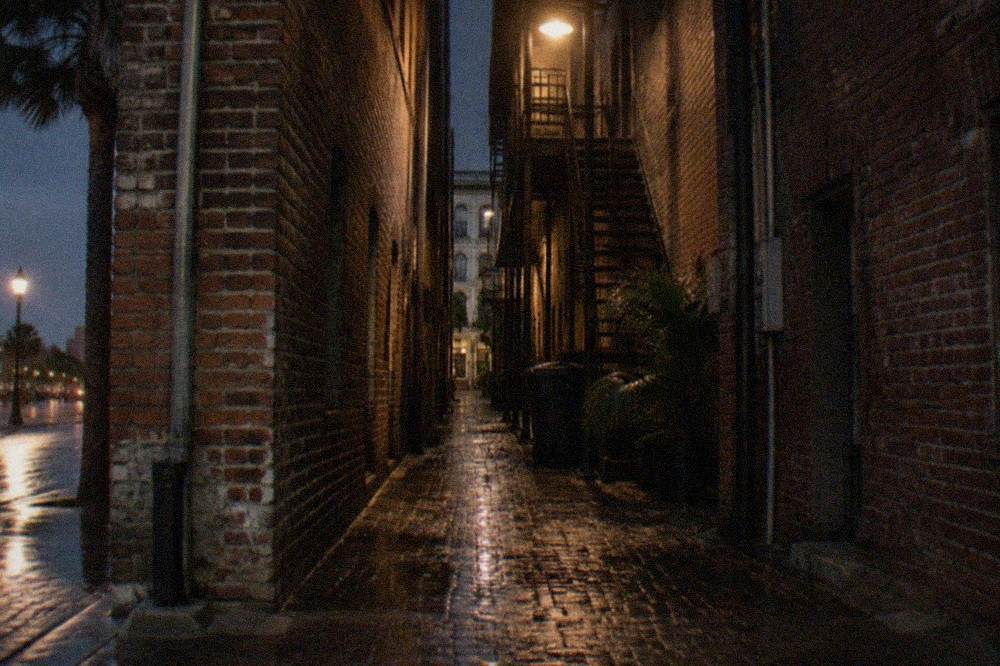 A narrow brick alley between historic Strand buildings lit by evening lamps