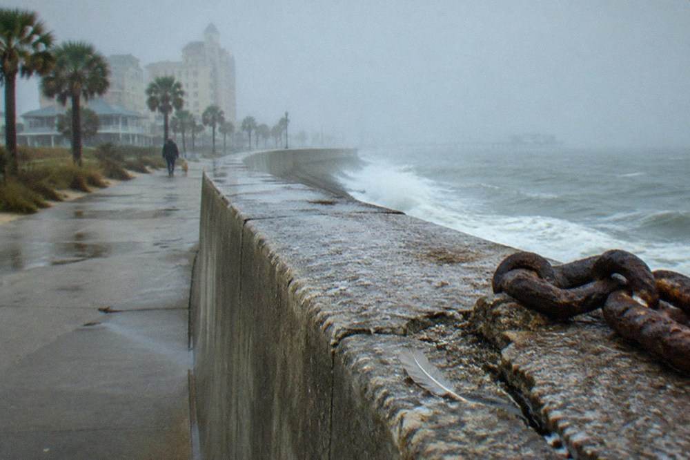 A long concrete seawall curving along a waterfront under an open sky