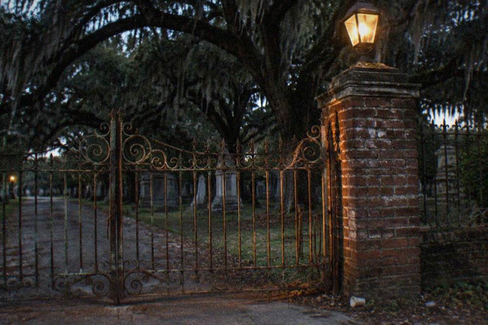 A dimly lit historic cemetery entrance with wrought iron gates