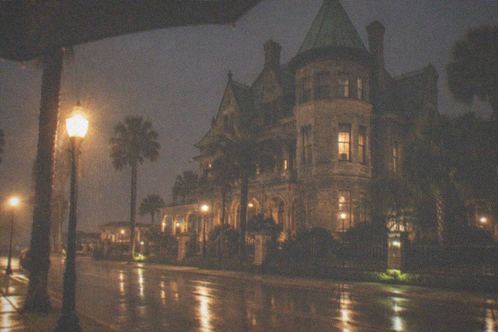 A Victorian mansion facade lit by street lamps at night