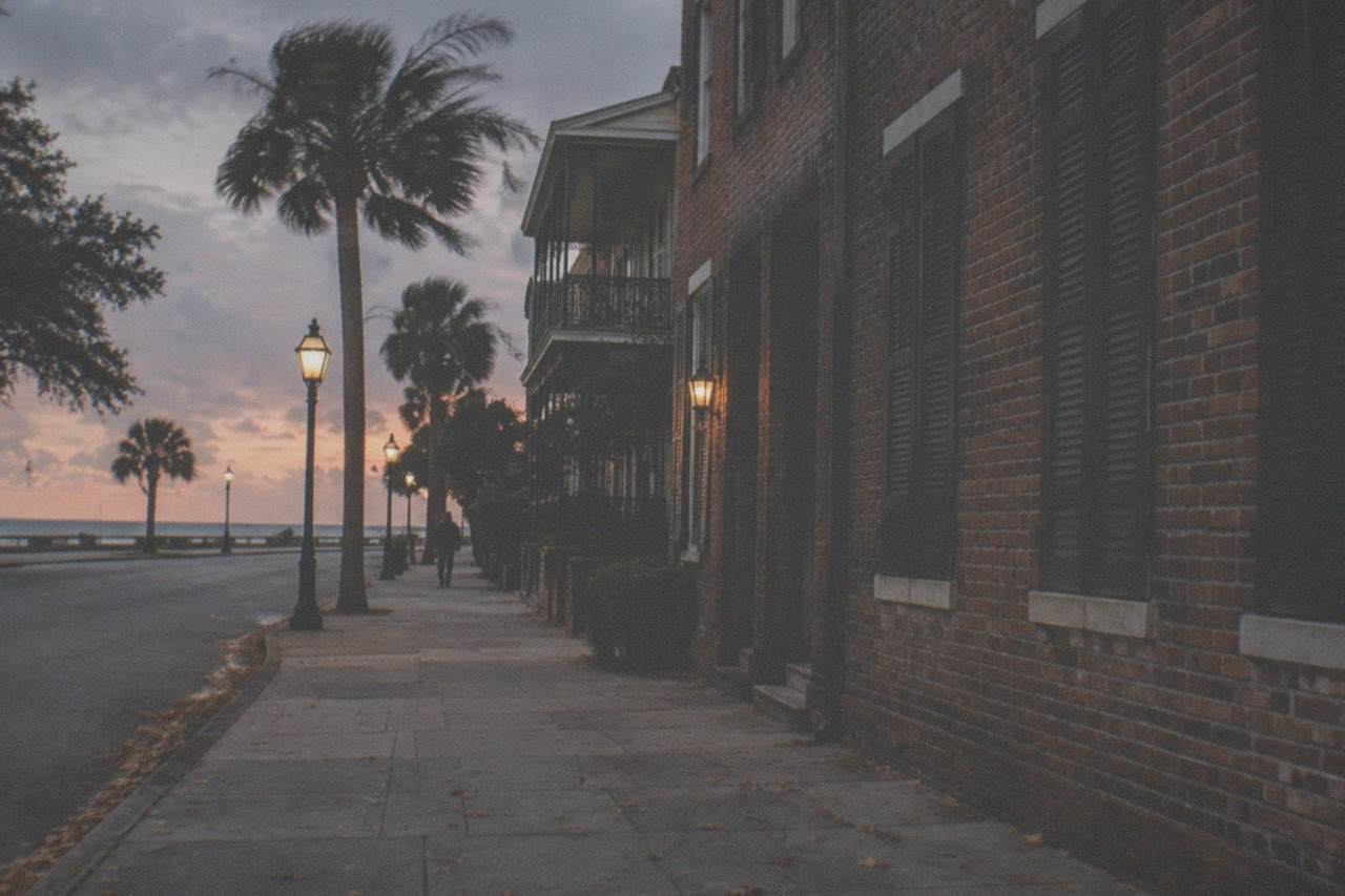 A quiet Galveston street at dusk with historic brick buildings and glowing lamps