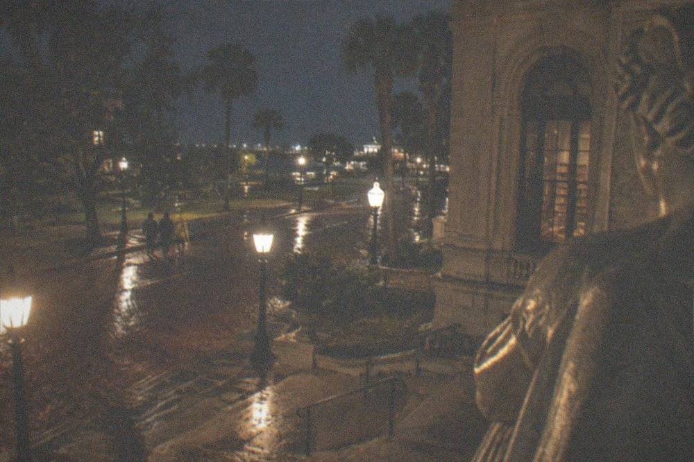 Gas-lit style streetlamps lining a historic brick street in the evening