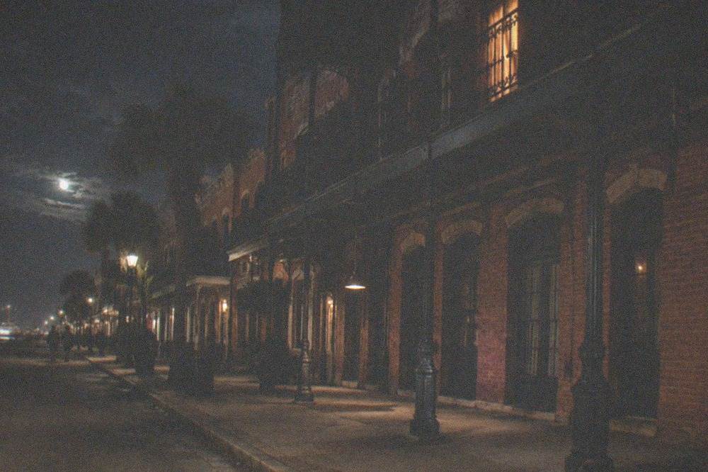 A historic brick hotel facade with cast-iron balconies above a lit downtown street.