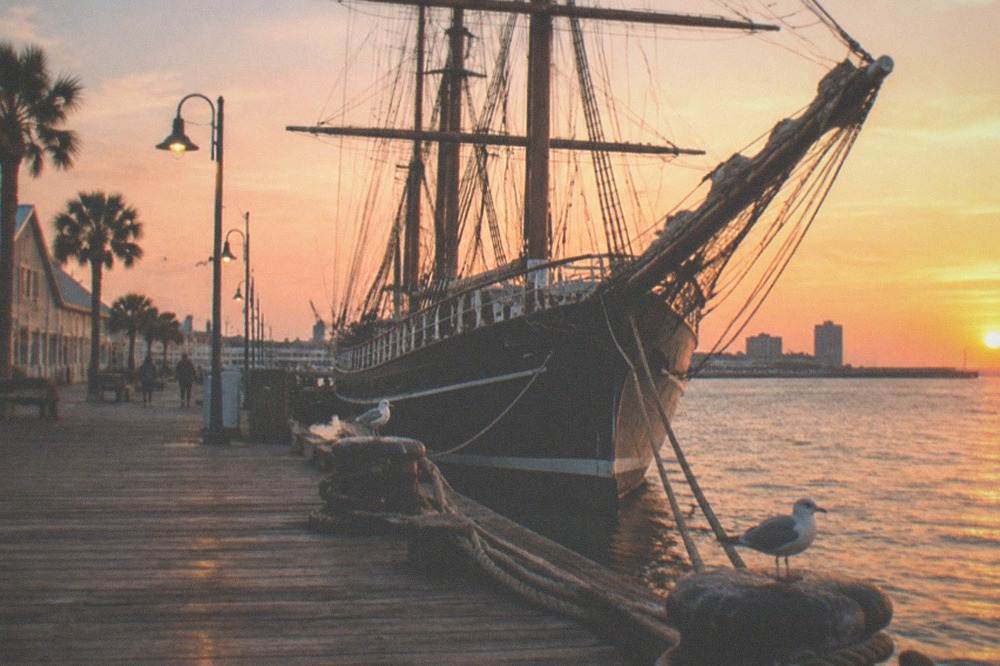 Restored 19th century tall ship with masts and rigging docked at a historic seaport